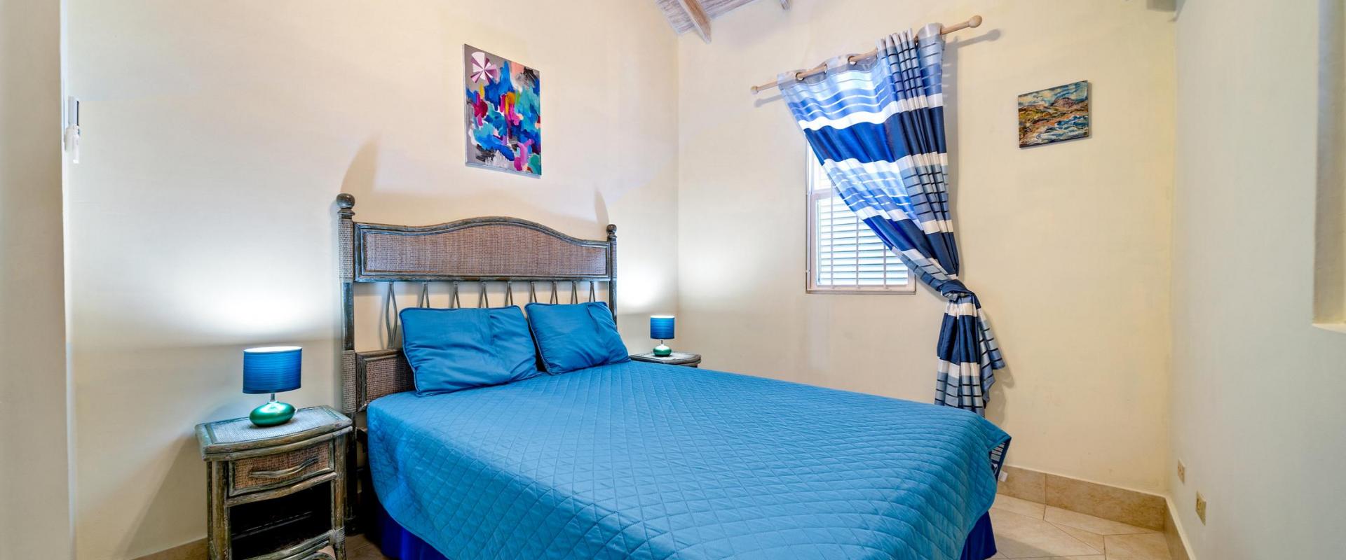 Inviting third bedroom with AC unit, bright décor, and queen bed with colorful bedding at Blue Waters 1 holiday rental in Barbados.