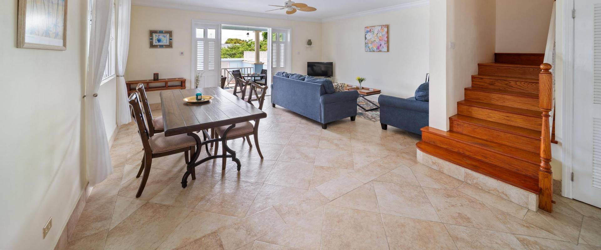 Open-concept living and dining room with cozy seating, dining table, and easy flow to the outdoor patio and pool at Blue Waters 1 holiday villa.