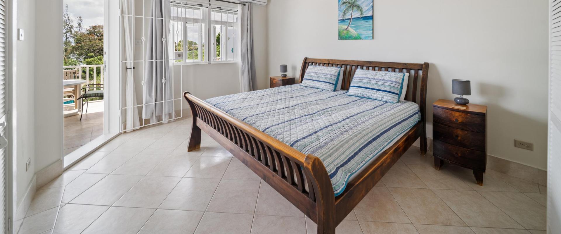 Large master bedroom with vaulted ceilings, air conditioning, and doors opening onto a private patio with ocean views at Blue Waters 1 villa Barbados.