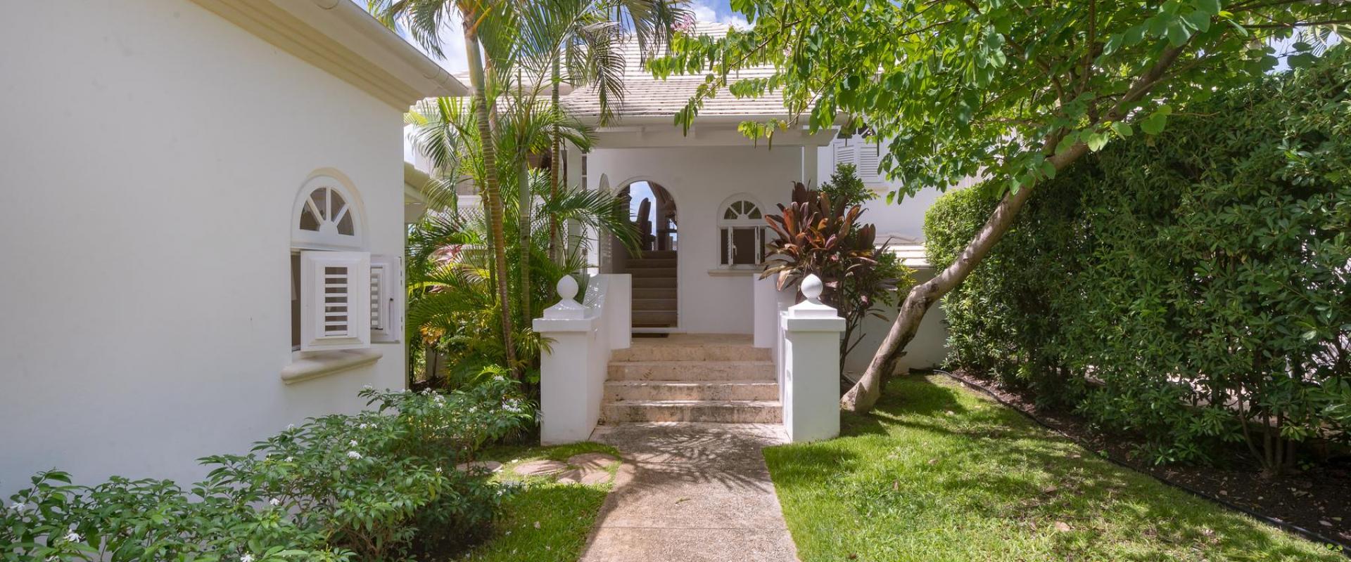 Tropical entrance to Forest Hills 23, featuring a beautifully landscaped pathway, lush greenery, and a charming island-style villa exterior.