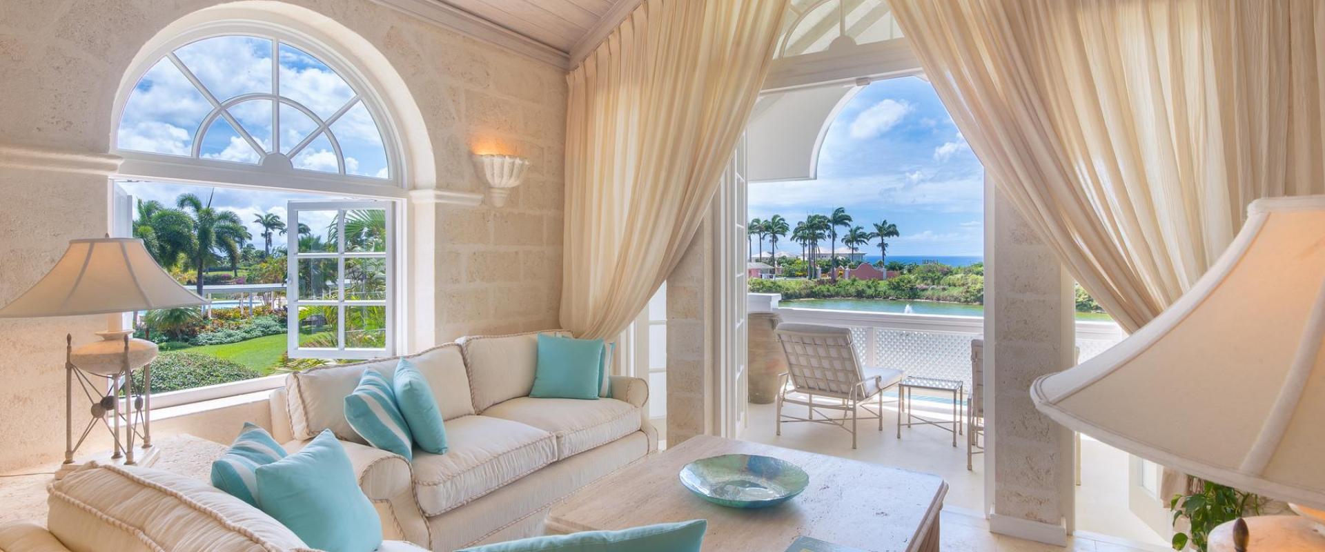 Bright and airy living room at Forest Hills 23, Barbados, with arched windows, comfortable seating, and a patio overlooking lush gardens and the ocean.