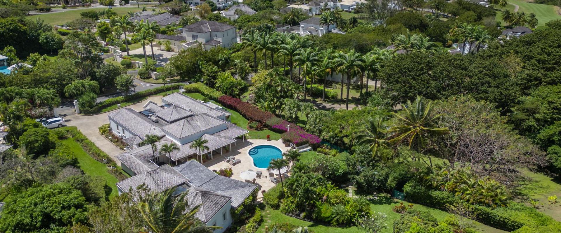 Tranquil pool area at Ixora Villa with surrounding gardens, lounge chairs, and parasols for relaxation