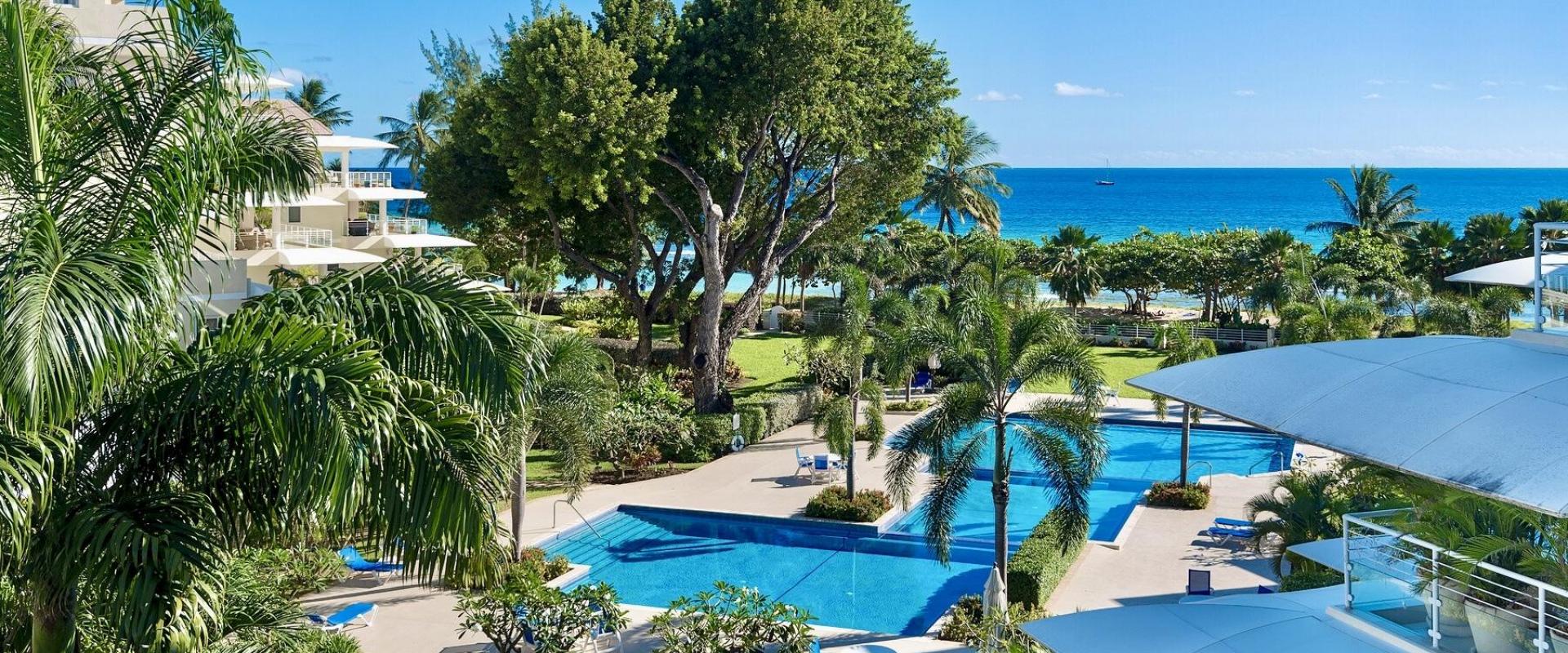 A breathtaking balcony view overlooking the resort-style swimming pools, tropical landscaping, and the crystal-clear waters of the Caribbean Sea at Palm Beach 101.
