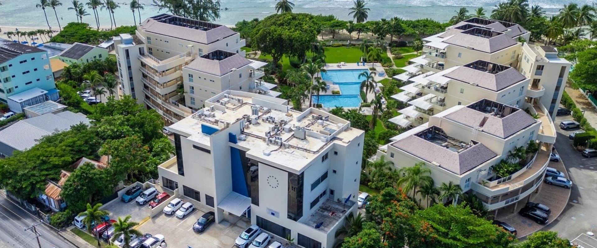 A striking aerial view of Palm Beach 101 in Barbados, showing the resort’s beachfront location, pools, lush gardens, and luxury accommodations.