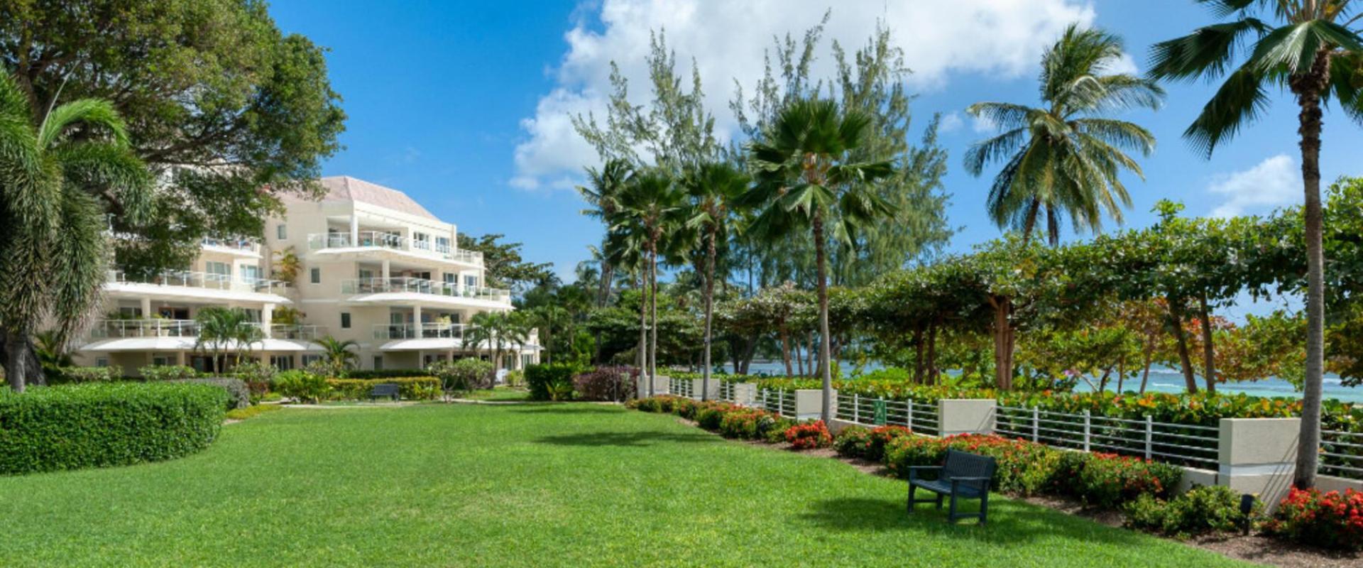 A scenic view of the manicured lawns and private beach access gate leading to the white sandy shores of Barbados’ South Coast.