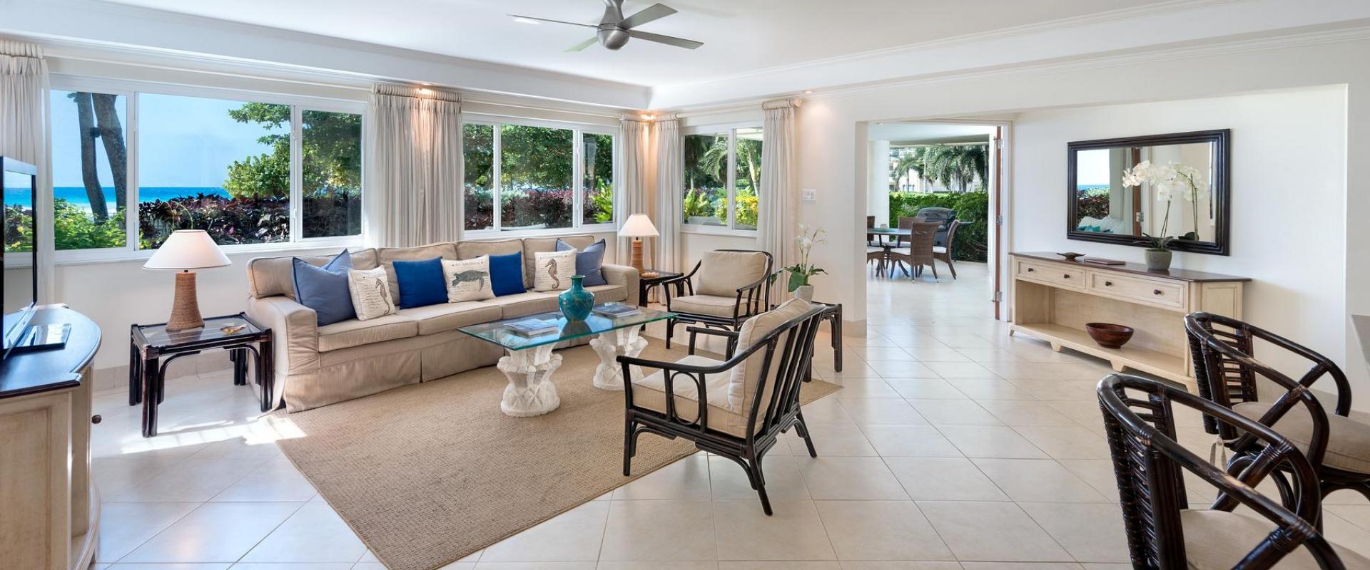 A beautifully designed living room at Palm Beach 101, Barbados, with plush seating, natural light, and large windows showcasing stunning ocean views.