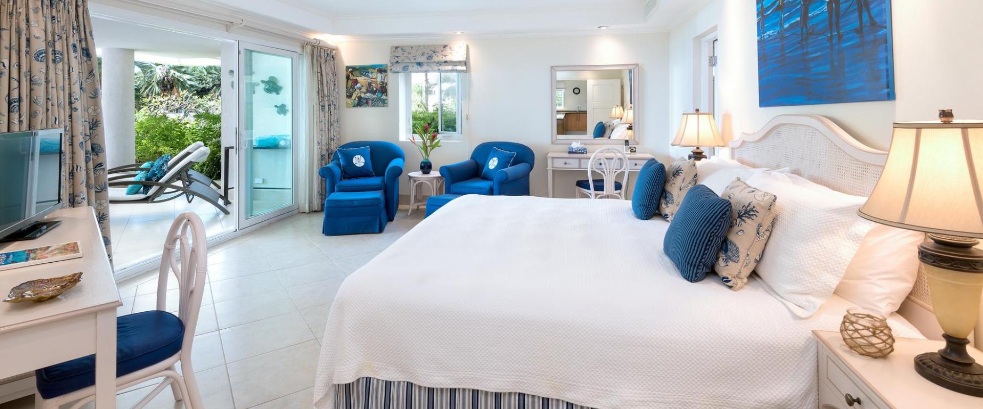 A tranquil master bedroom at Palm Beach 101 in Barbados, featuring a king-size bed, stylish coastal decor, and direct access to a private patio.