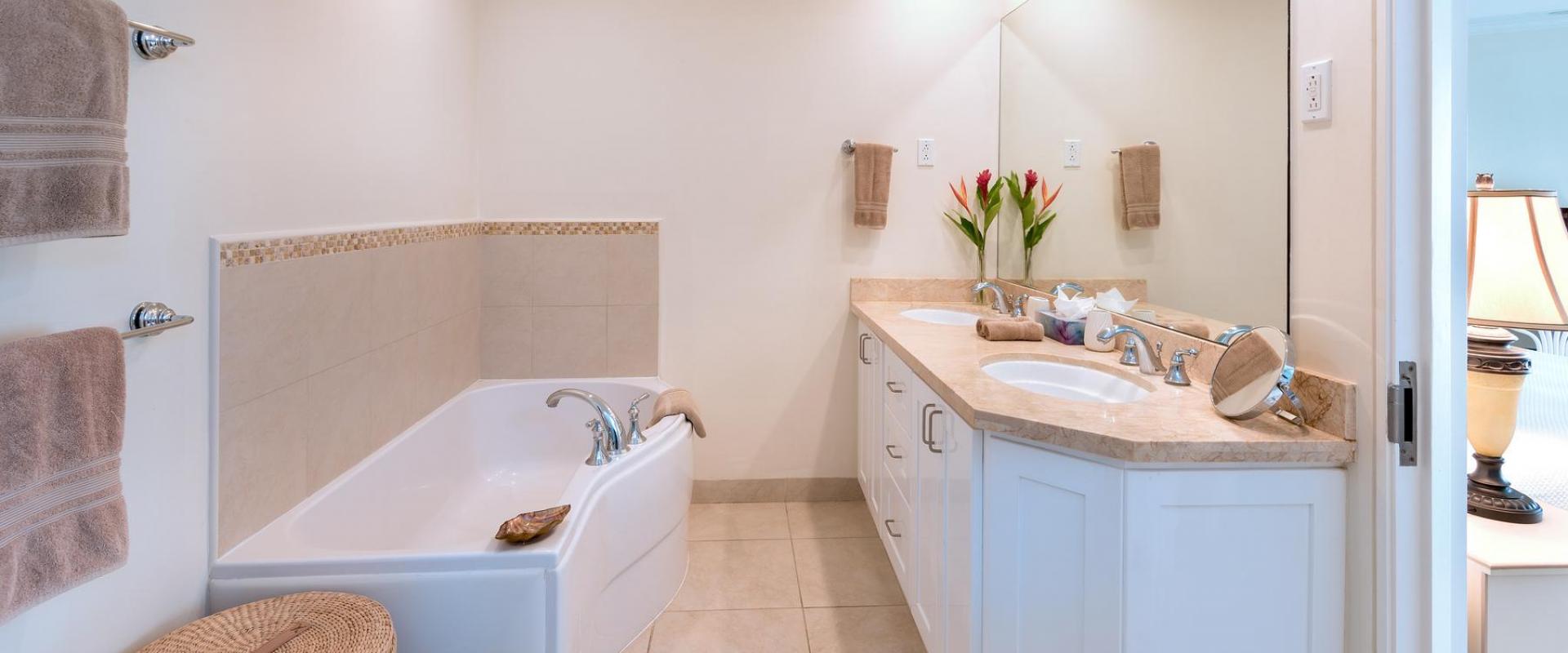 A spa-inspired master bathroom at Palm Beach 101, featuring a deep soaking tub, dual vanity with marble countertops, and soft ambient lighting.