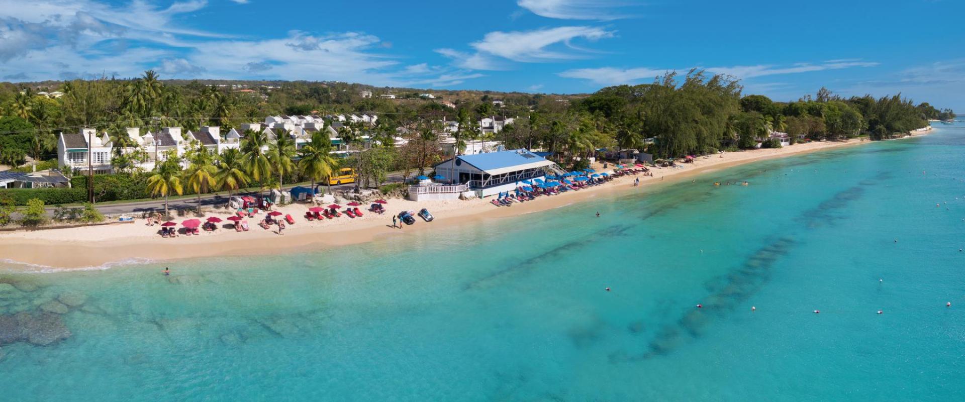 Aerial view of Mullins Beach, showcasing pristine waters, beach loungers, and a vibrant beachfront restaurant in Barbados.