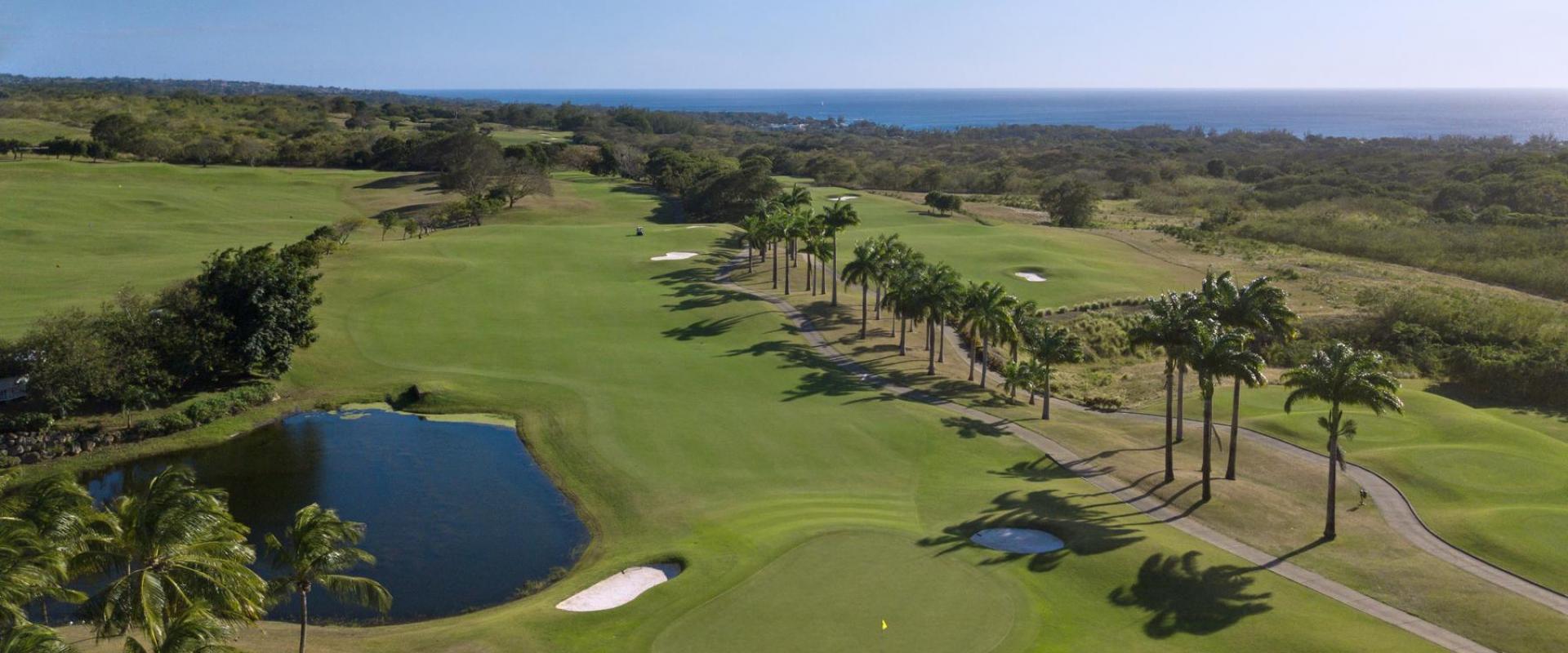 Breathtaking aerial view of the championship golf course at Royal Westmoreland, Barbados, with lush fairways, palm trees, and ocean vistas.