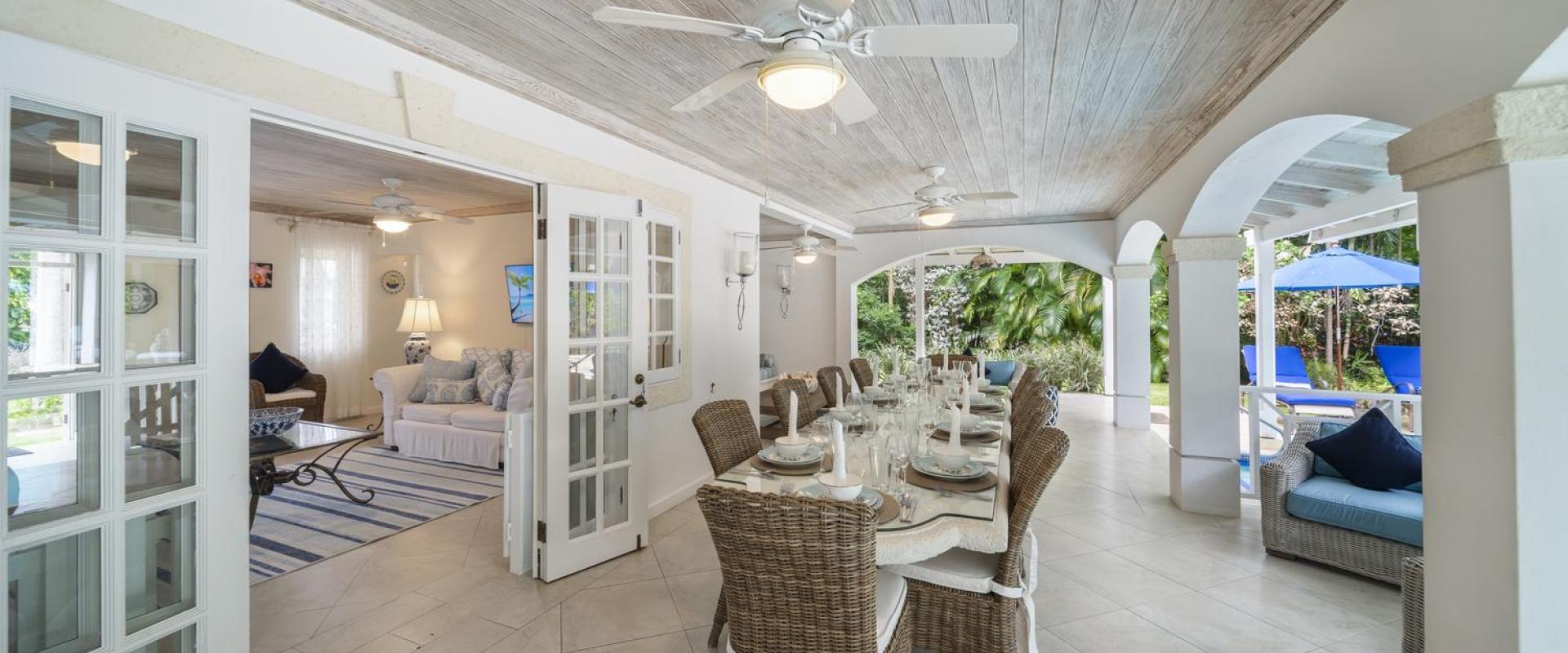 Covered outdoor dining area at Sandalwood House, Barbados, with seating for guests and easy access to the living room and pool.