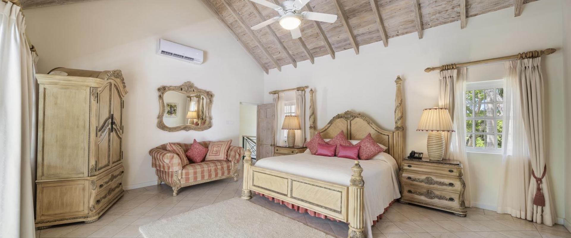 Luxurious primary bedroom at Sandalwood House with high vaulted ceilings, elegant furnishings, and a king-sized bed.