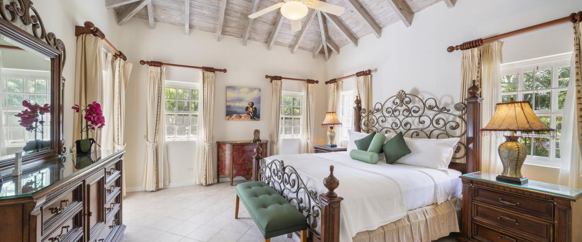 Second bedroom at Sandalwood House, featuring an ornate iron bed, vaulted ceilings, and stylish decor.