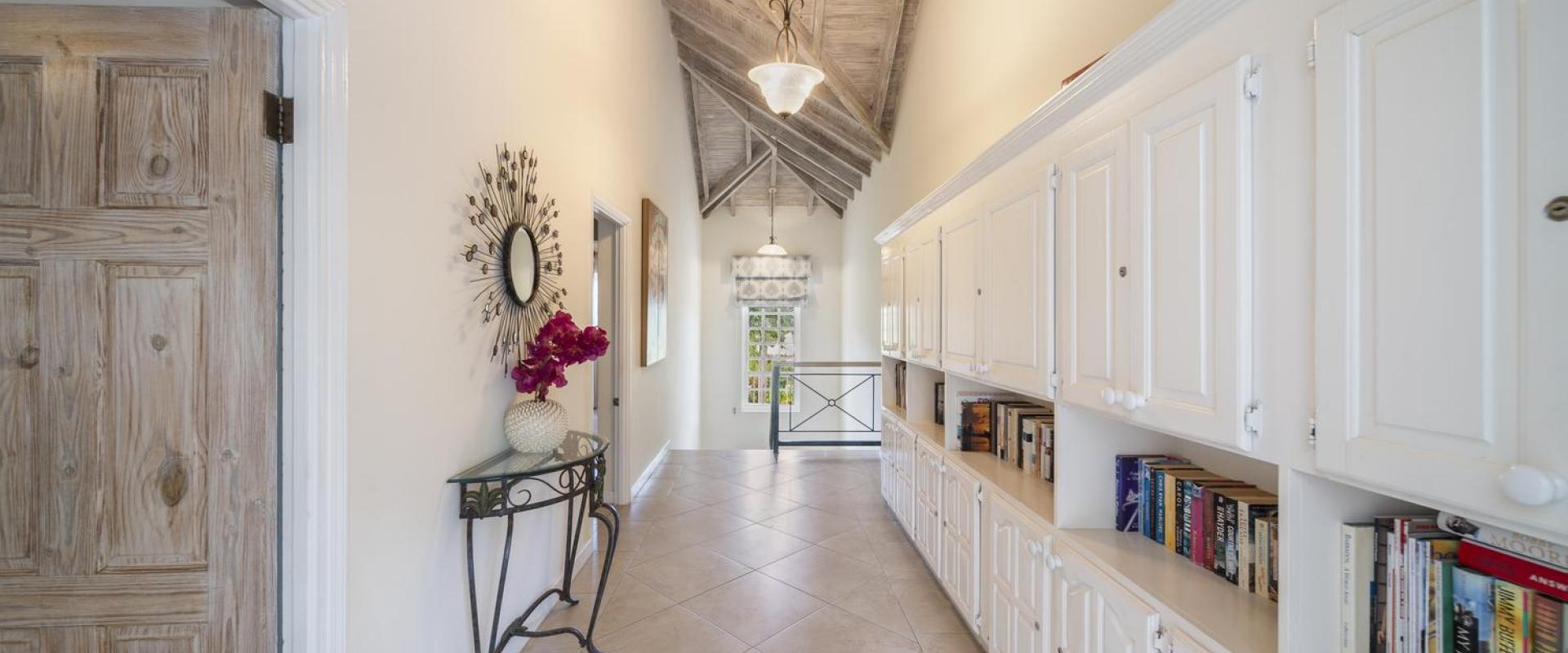 Hallway at Sandalwood House, showcasing built-in bookshelves and a vaulted wooden ceiling.