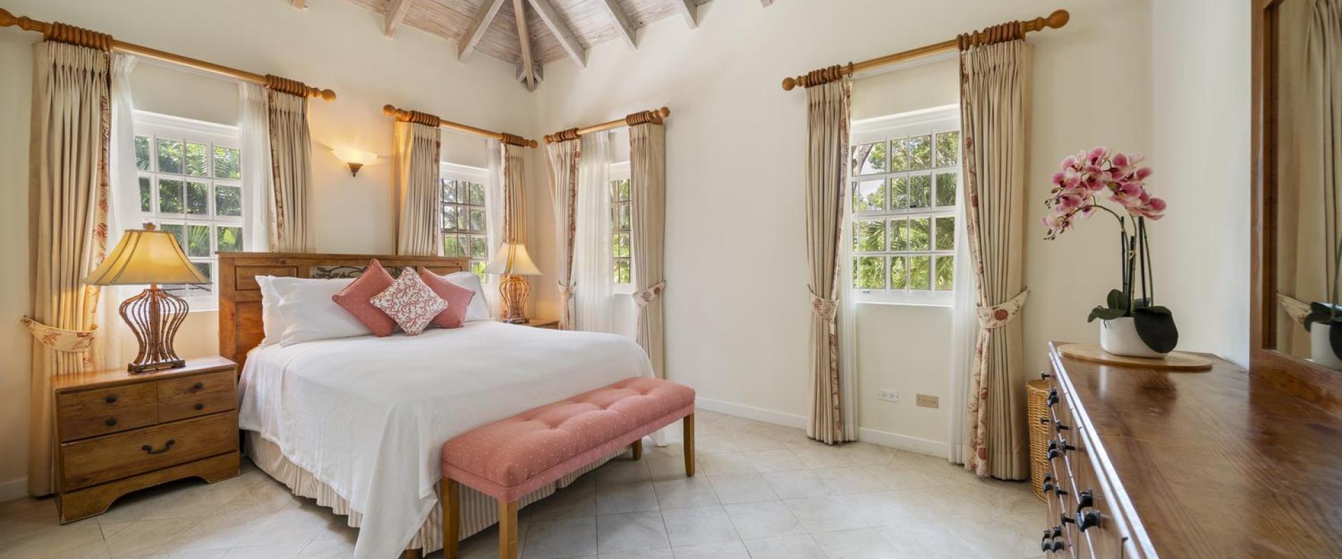 Third bedroom at Sandalwood House, featuring a king-sized bed, vaulted ceilings, and natural light from large windows.