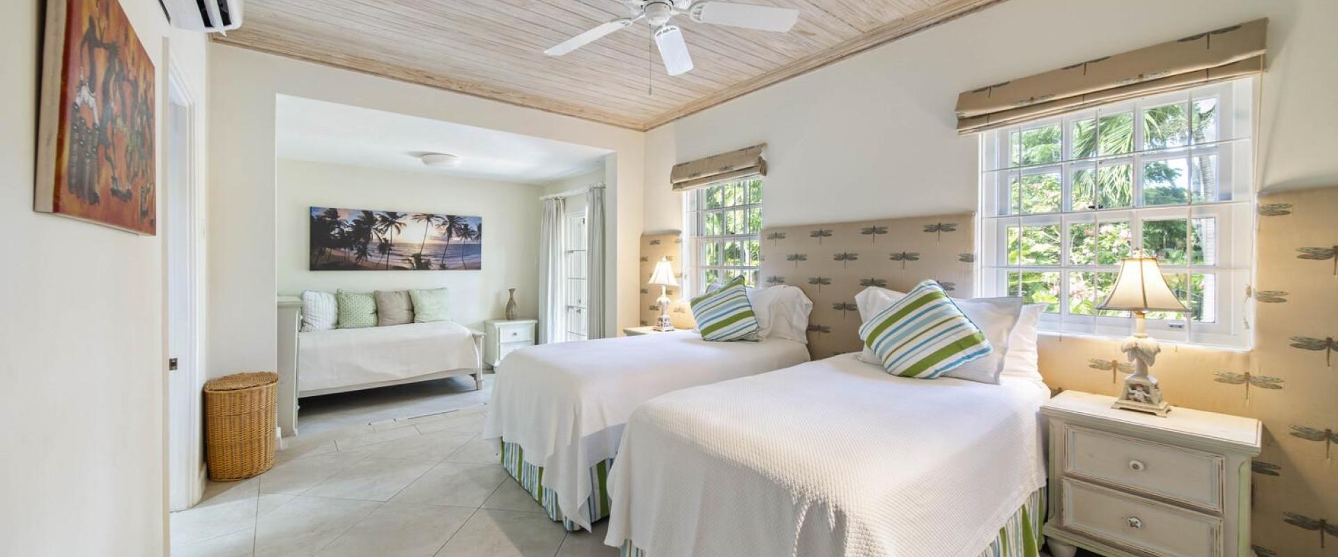 Bright and airy twin bedroom at Sandalwood House, with two beds, stylish striped cushions, and a seating area with garden views