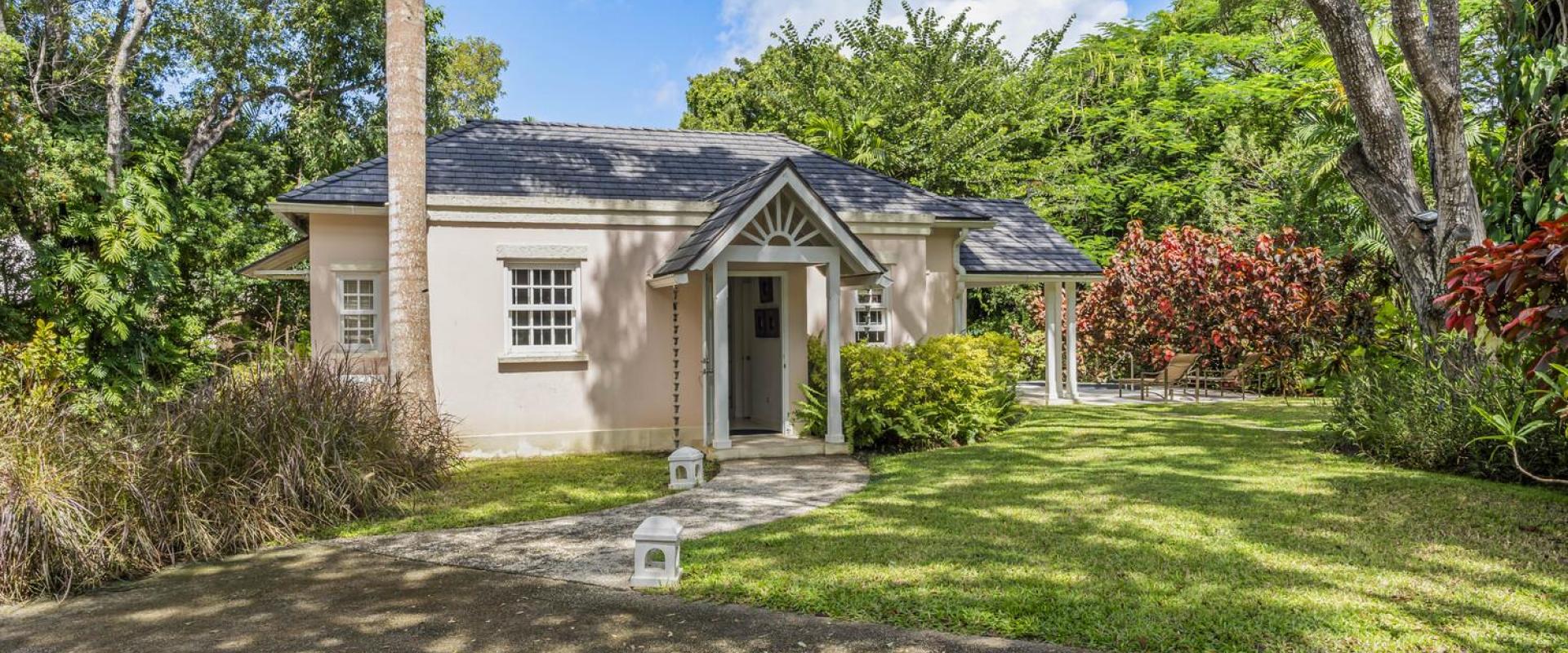 Charming garden cottage at Sandalwood House, nestled within the lush greenery, featuring a quaint gabled entrance