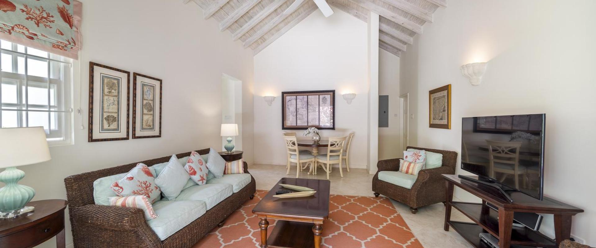 Spacious living and dining area at Cottage of Sandalwood House, with wicker furniture, vaulted ceilings, and a cozy dining nook