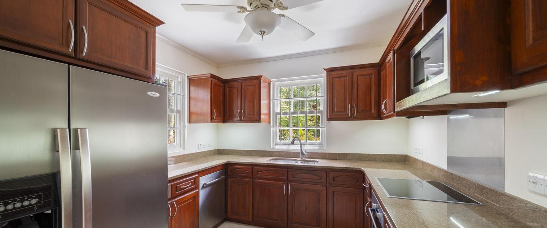 Fully equipped kitchen at Cottage of Sandalwood House, featuring rich wooden cabinetry, granite countertops, and stainless steel appliances.