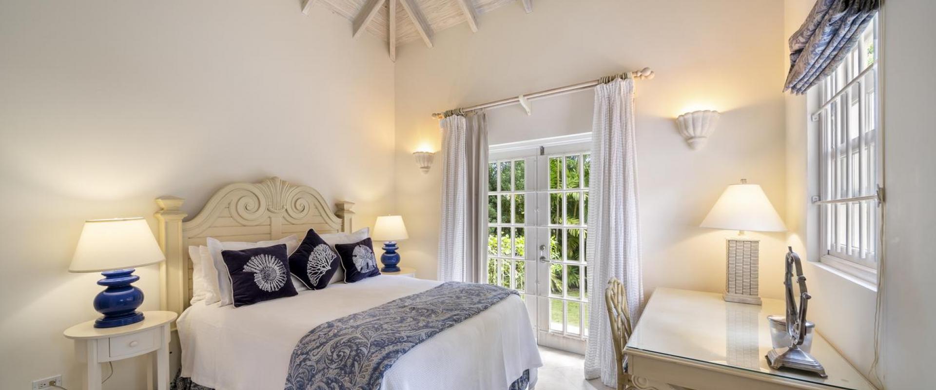 Cottage bedroom one at Sandalwood House with high vaulted ceilings, a king-sized bed, and elegant blue and white decor