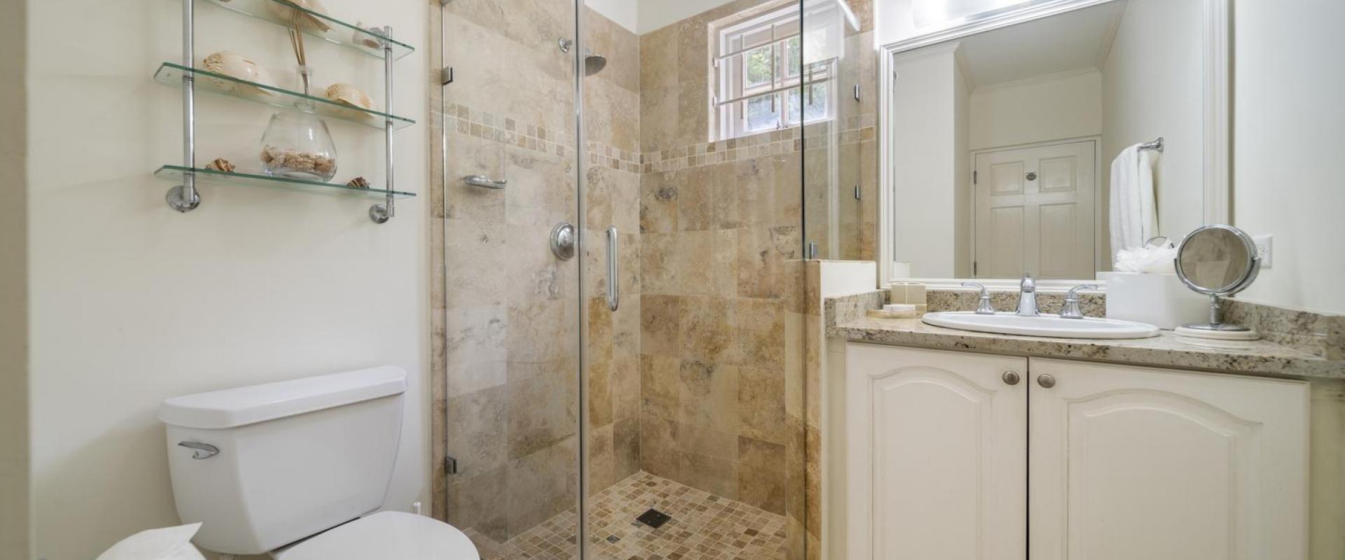 Bathroom two of Cottage at Sandalwood House with glass shower, floating shelves, and polished stone finishes