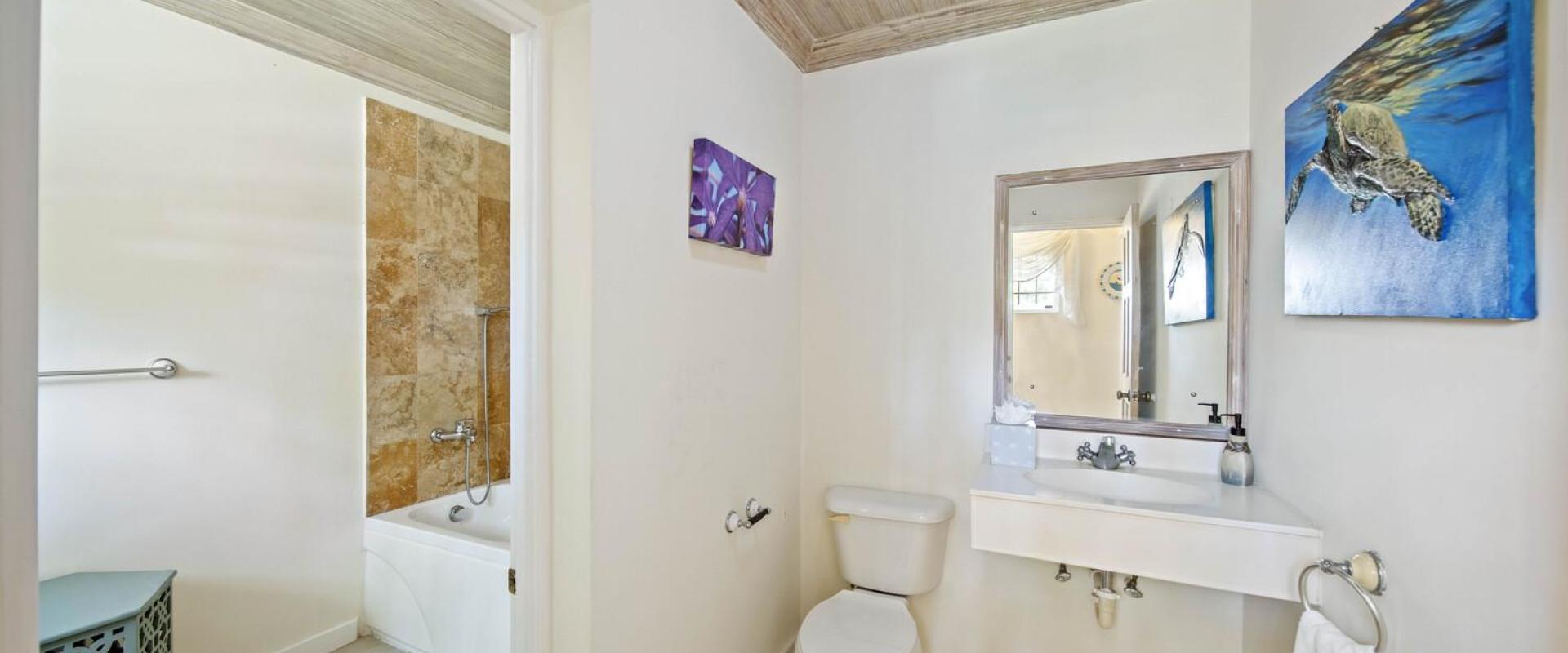 Full guest bathroom at Sandalwood House featuring natural wood ceiling, stone-tiled walls, and a soaking tub