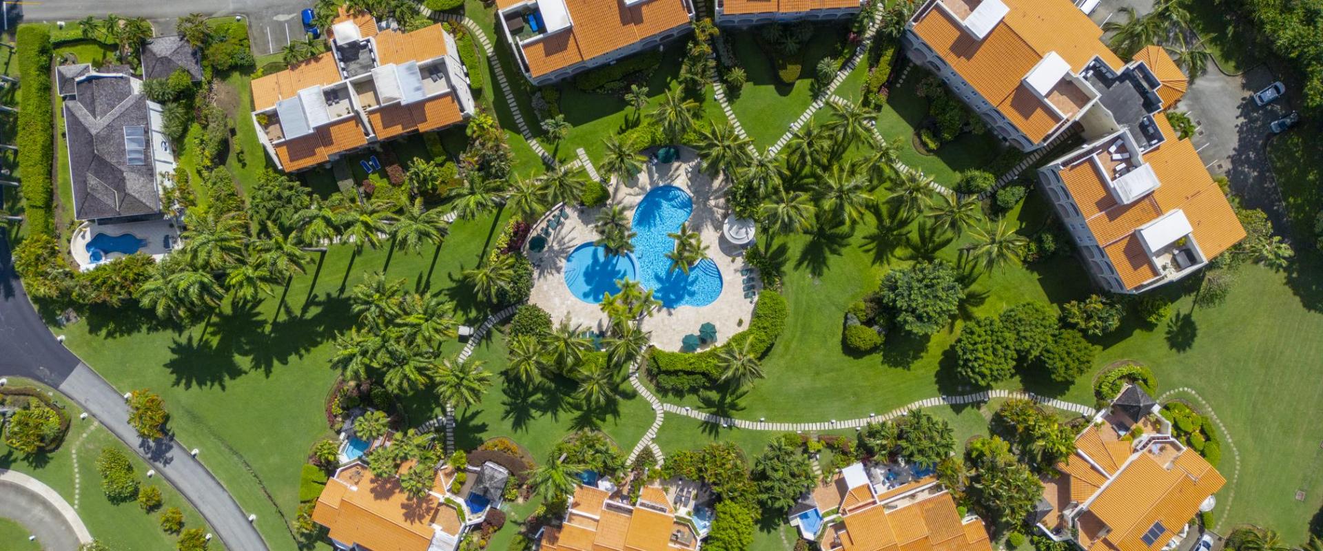 Aerial view of Sugar Hill Resort, Barbados, featuring the lush landscaped grounds, tropical palm trees, and the central pool area, with the Seabreeze Penthouse nestled among luxury villas, showcasing its prime location in this upscale resort.