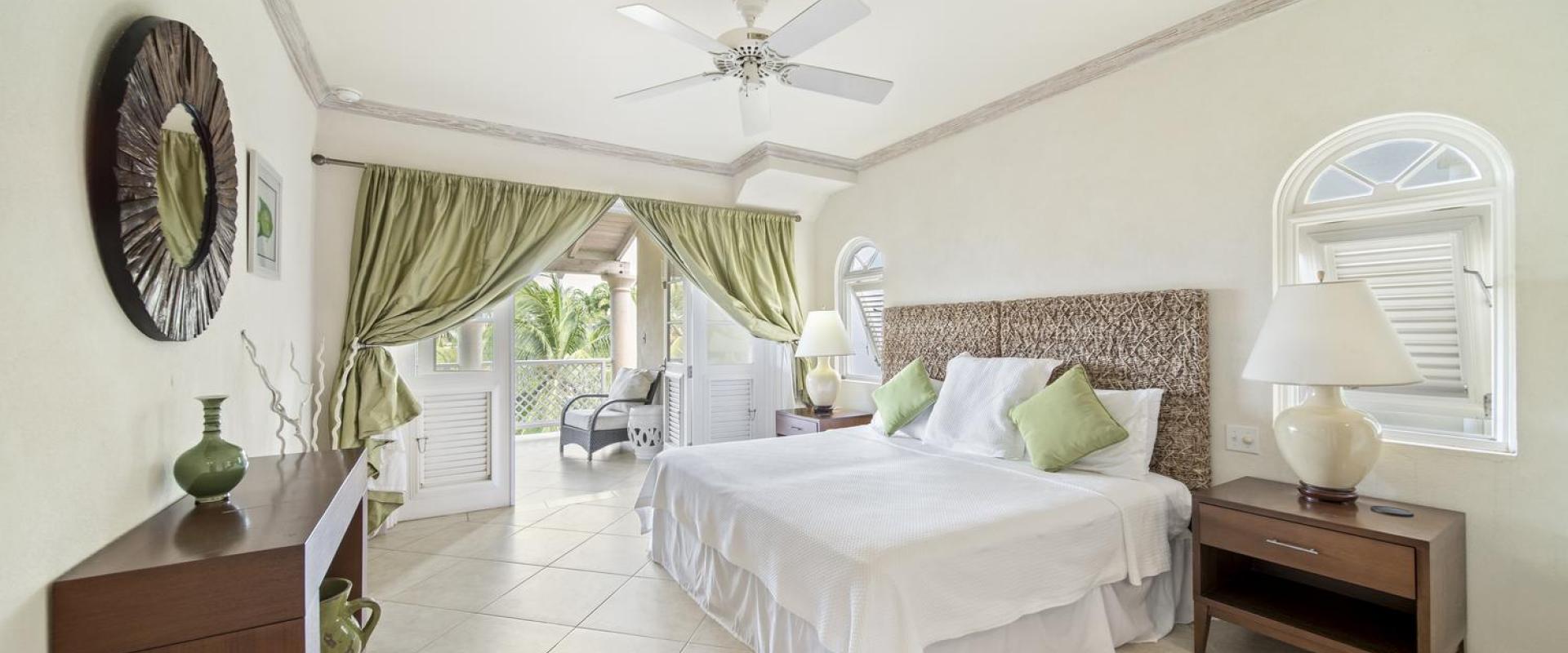 Elegant bedroom in Seabreeze Penthouse, Sugar Hill Resort, Barbados, with a comfortable queen-size bed, soft green accents, and direct access to a private balcony with views of tropical palm trees, creating a serene and restful atmosphere.