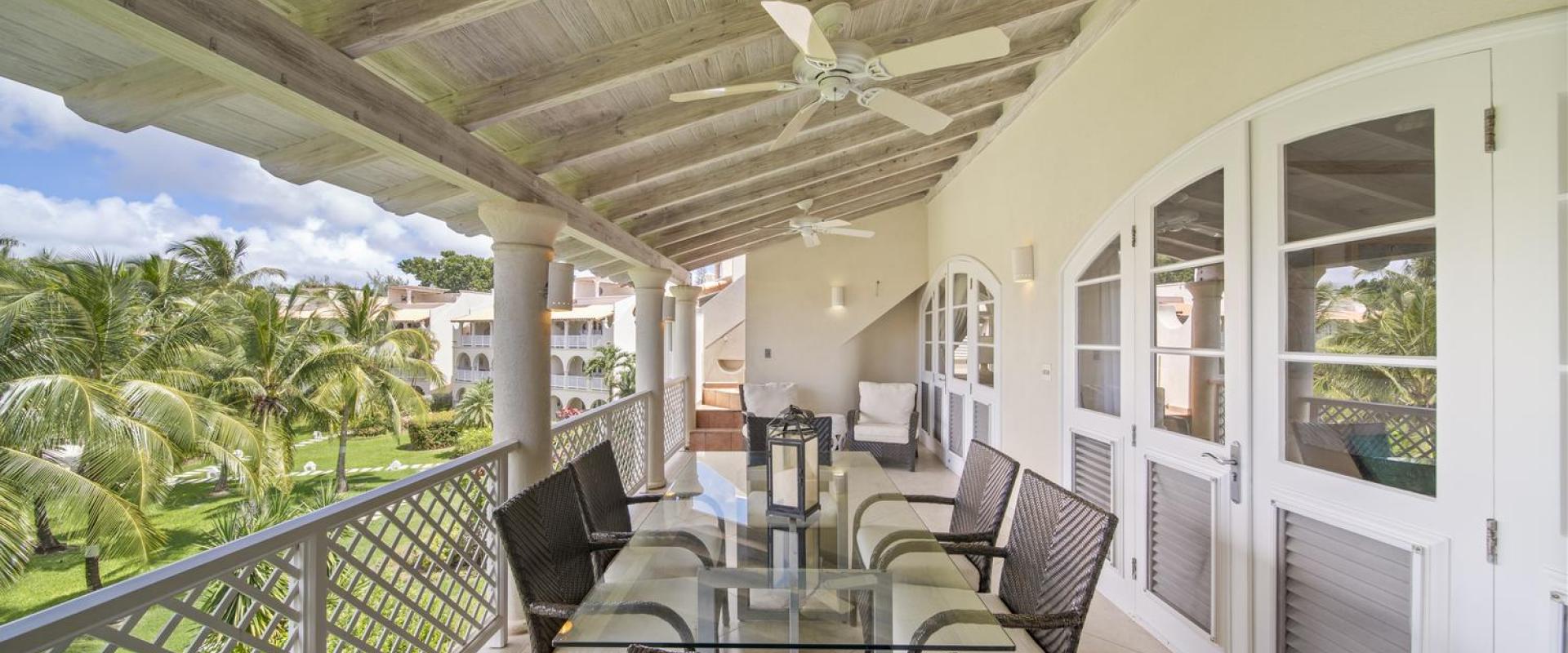 Private balcony of Seabreeze Penthouse at Sugar Hill Resort, Barbados, with outdoor dining area, wicker furniture, and ceiling fans, offering a relaxing space to enjoy views of the resort's lush gardens and Caribbean breezes.