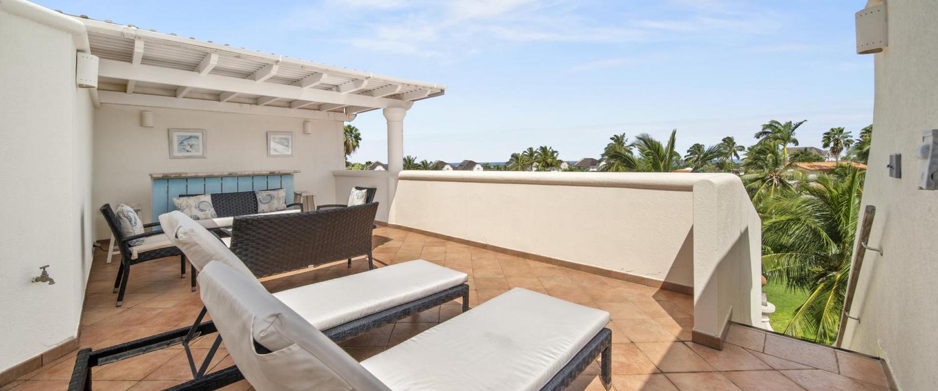 Rooftop terrace of Seabreeze Penthouse, Sugar Hill Resort, Barbados, featuring sun loungers, cozy seating area, and partial sea views, perfect for sunbathing or evening relaxation with picturesque surroundings.