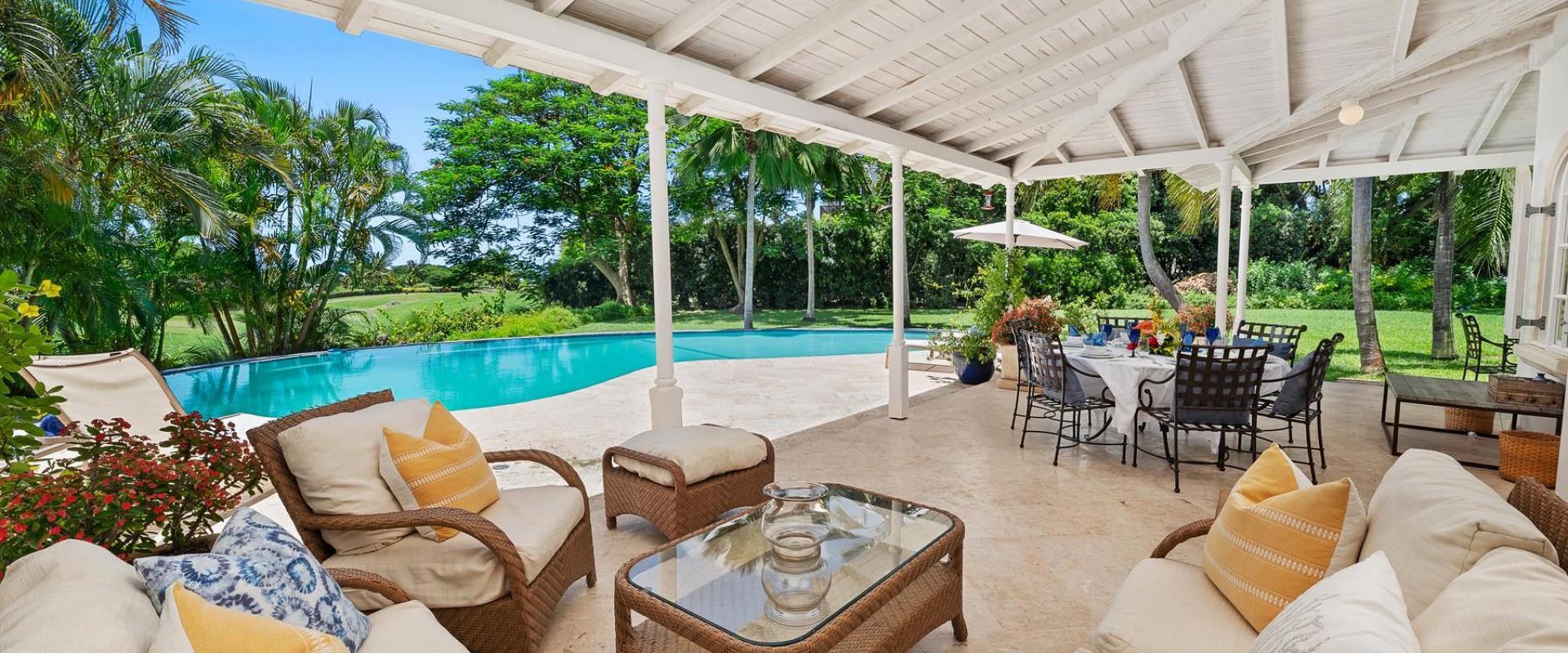 Elegant covered patio at Villa Rosa, offering an outdoor dining and lounging space with pool and garden views.