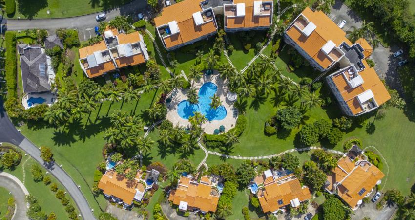 Aerial view of Sugar Hill Resort, Barbados, featuring the lush landscaped grounds, tropical palm trees, and the central pool area, with the Seabreeze Penthouse nestled among luxury villas, showcasing its prime location in this upscale resort.